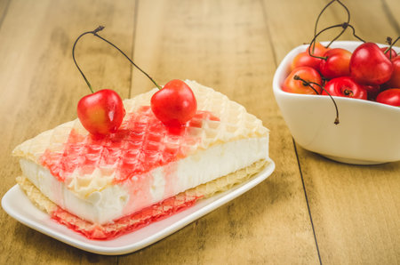 Ice cream and sweet cherry in a white plate on a wooden background / wafer ice cream with sweet cherryの写真素材