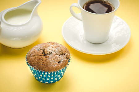 Tasty cupcake on a background a cup and a creamer / tasty cake on a background a white cup and a creamerの写真素材