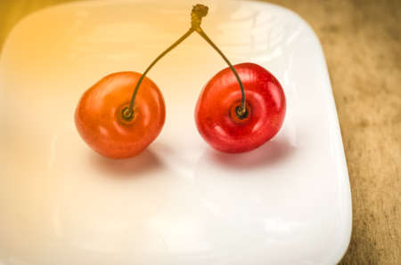Two cherries in a white saucer / two sweet cherries in a white saucerの写真素材