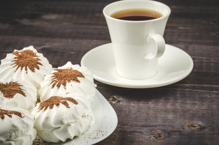 White zephyr marshmallows and white cup with coffee / white zephyr marshmallows and white cup with coffee on a wooden backgroundの写真素材