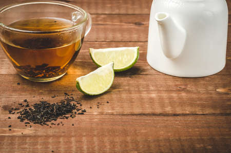 tea on a wooden table with a lime and a white teapot / tea with a lime and a white teapotの写真素材