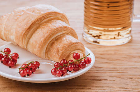 croissant with red berries and glass with teacroissant with red berries in white bowl and glass with tea. Tonedの写真素材
