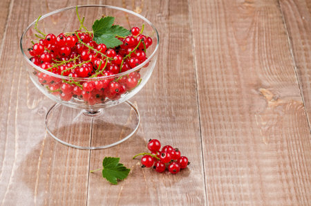 glass bowl full of red currantglass bowl full of red currant on a wooden background. With copy spaceの写真素材