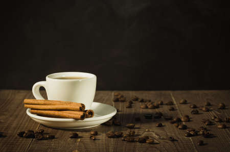 white cup about coffee and the scattered coffee beans on a wooden background/white cup about coffee and the scattered coffee beans on a wooden background. With copy spaceの写真素材
