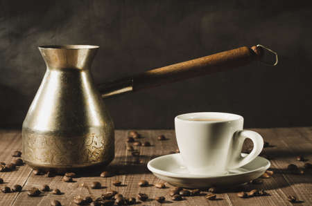 white cup and the coffeemaker with hot steam on a wooden background/white cup and the coffeemaker with hot steam on a wooden background. selective focusの写真素材