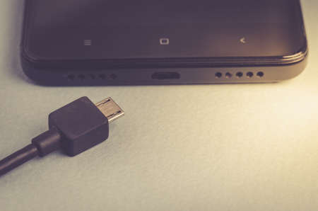 black Smartphone with charger. Toned. Cope spaceの写真素材