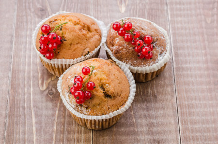 Cupcakes decorated with red currant on a wooden background. top viewの写真素材