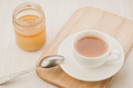 white Cup of tea on a wooden tray and jar of honey. Selective focusの写真素材