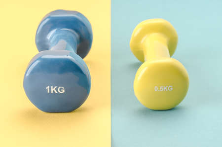 Fitness concept with dumbbells/blue dumbbell on a yellow background yellow on blue. Close up. selective focusの写真素材