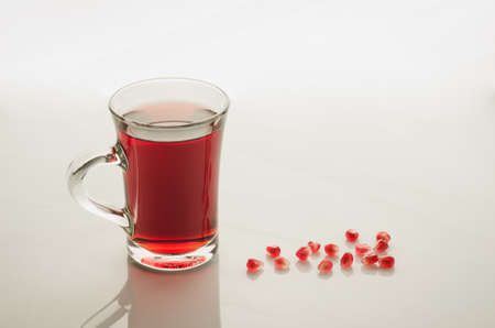 glass of garnet juice and grain on a white marble/glass of garnet juice and grain on a white marble. selective focus

の写真素材