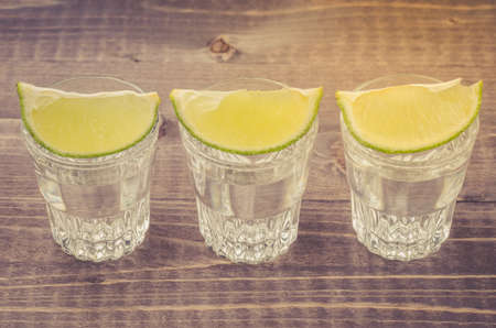 glasses of tequila with a lime stand in a row/glasses of tequila with a lime stand in a row.  Top viewの写真素材