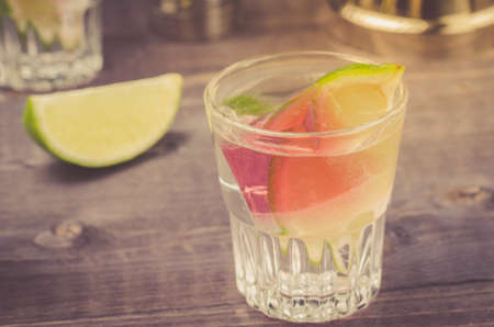 shot with ice and a lime/shot with ice and a lime on a wooden background. selective focusの写真素材