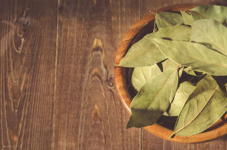 bay leaf in a wooden bowl/bay leaf in a wooden bowl on a wooden background. Top view. Copy spaceの写真素材