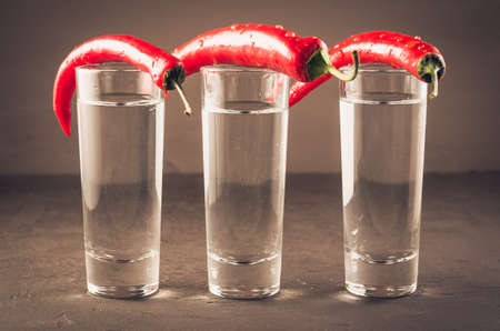 shots of vodka and red pepper/shots of vodka and red pepper on a dark stone background. Selective focusの写真素材