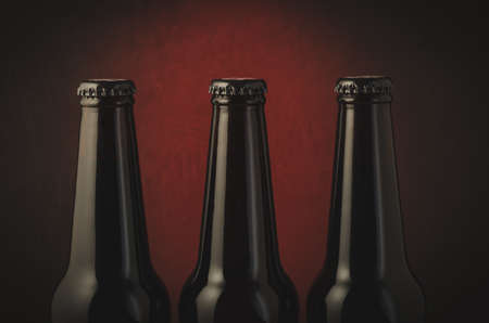 Three black bottle of beer on a dark background with red light/Three black bottle of beer on a dark background with red light. Selective focusの写真素材
