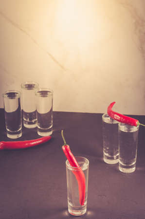 Drink set with shots of vodka and red pepper/Drink set with shots of vodka and red pepper on a white marble background. Selective focus. Tonedの写真素材