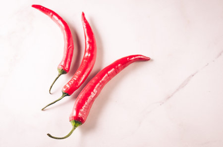 red Chile on white stone background/shining red hot pepper on a white background. Top view. Copy...
