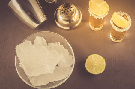 bar concept: Tequila shots, lime, ice and shaker/Tequila shots, lime, ice and shaker on a dark background. Top viewの写真素材