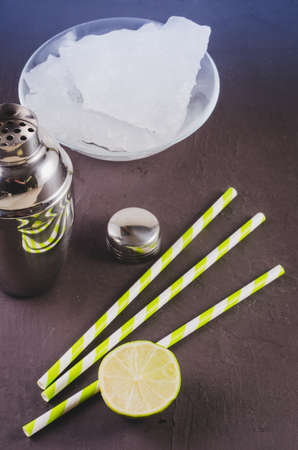 Cocktail shaker, lime, ice and straws on a dark background. Top viewの写真素材
