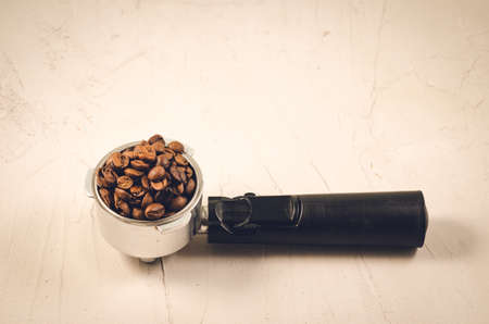 holder filled with coffee beans/Filter holder filled with coffee beans on a concrete background. Copyspaceの写真素材