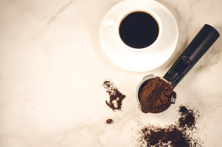 holder filled with ground coffee and a white cup/holder filled with ground coffee and a white cup on...