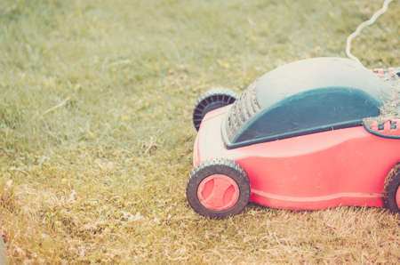 red lawn mower on the lawn/red lawn mower on the green lawn. Copyspace. Tonedの写真素材