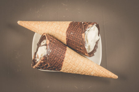 two ice cream with cone in chocolate on a dark background/two ice cream with cone in chocolate, top...