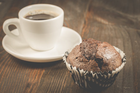 cup of black coffee and a chocolate muffin/cup of black coffee and a chocolate muffin on a dark...