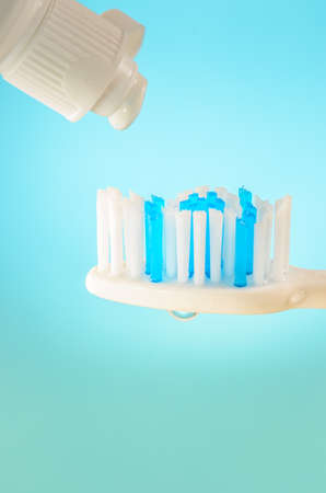 Toothpaste squeezed from tube onto brush on a blue background, close up. Stomatology conceptの写真素材
