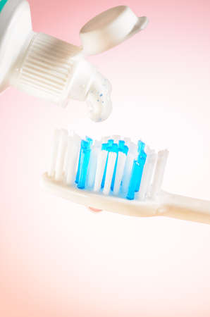 Toothpaste squeezed from tube onto brush on a pink background, close upの写真素材