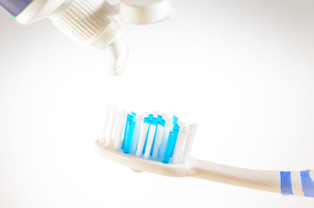 Toothpaste squeezed from tube onto brush on a white background, close up