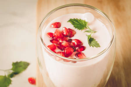 Yogurt. Yogurt with garnet and mint in glass on a wooden tray. Top view. Sweet dessertの写真素材