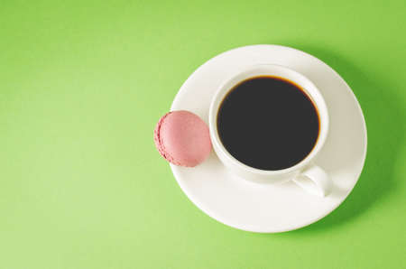 sweet macaroons or macaron and coffee white cup on a green background, top view and copy space. French dessertの写真素材