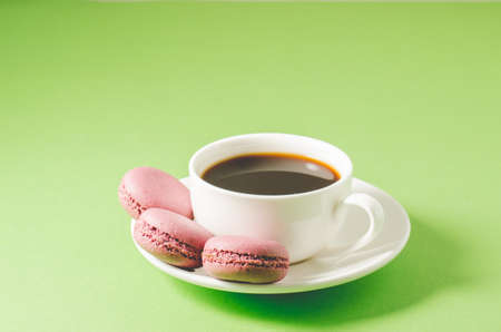 sweet macaroons or macaron and coffee white cup on a green background, close up. French dessertの写真素材