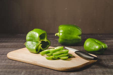 fresh paprika cut on a wooden board/fresh paprika cut on a wooden board on a dark background, selective focusの写真素材