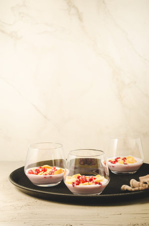 yogurt with pomegranate and flakes on a black tray/homemade yogurt with pomegranate and flakes in glass on a black tray and white background with copy spaceの写真素材