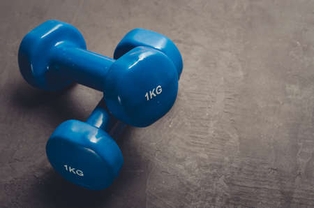 Blue dumbbells against a dark background/sports concept blue dumbbells against a dark background. Top view and copy spaceの写真素材