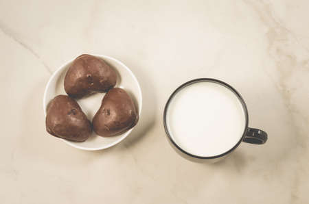 breakfast with chocolate gingerbreads and milk/chocolate gingerbreads and milk in a black mug on a white marble background. Top viewの写真素材