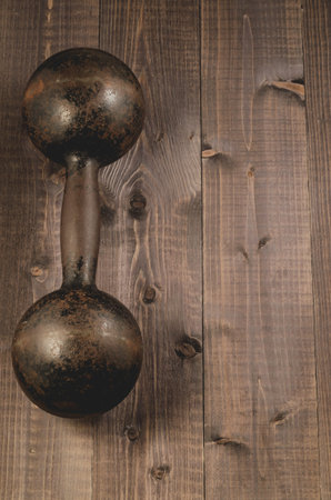 vintage iron dumbbell on the black wooden background/vintage iron dumbbell on the black wooden background, top view and copyspceの写真素材