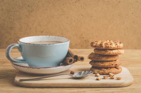 cinnamon sticks, cookies with nuts and a cup of coffee/cinnamon sticks, cookies with nuts and a cup of coffee on a wooden tray. Selective focusの写真素材