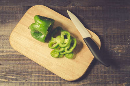 fresh paprika cut on a wooden board on a dark background/green pepper paprika cut on a wooden board and dark table, top viewの写真素材