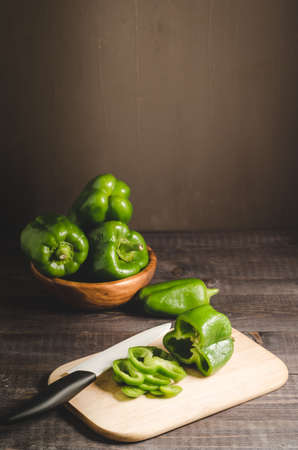 fresh paprika in a wooden bowl and cut on a board/fresh paprika in a wooden bowl and cut on a board on a dark background with copy spaceの写真素材