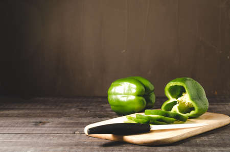 green paprika knifed white on a wooden board/green paprika knifed white on a wooden board on a dark background with copy spaceの写真素材