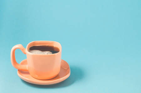 orange cup with black coffee on a blue background/orange cup of espresso with a skin on a blue background with copy spaceの写真素材