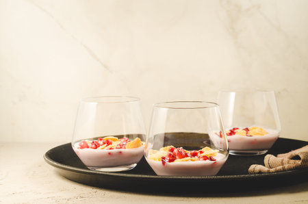 yogurt with pomegranate and flakes on a black tray/homemade yogurt with pomegranate and flakes in...