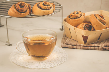 Breakfast whith rolls with poppy and glass cup whith tea/Breakfast whith rolls with poppy and glass cup whith tea. Focus on bread on a white table. Selective focusの写真素材