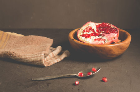 cut into pieces red garnet in a wooden bowl on the table/parts of pomegranate in a wooden bowl and a...