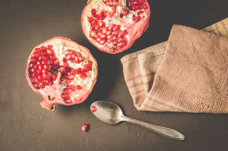 parts of pomegranate and a spoon on a table/parts of pomegranate and a spoon on a dark table, top viewの写真素材