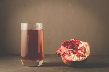 Pomegranate fruit and juice in glass/Pomegranate fruit and juice in glass on dark backgroundの写真素材