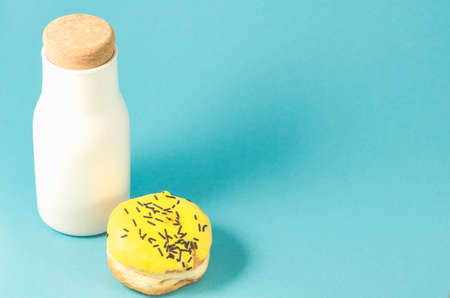Donut in yellow glaze and white bottle on blue background/Donut in yellow glaze and white bottle on blue background with copy spaceの写真素材